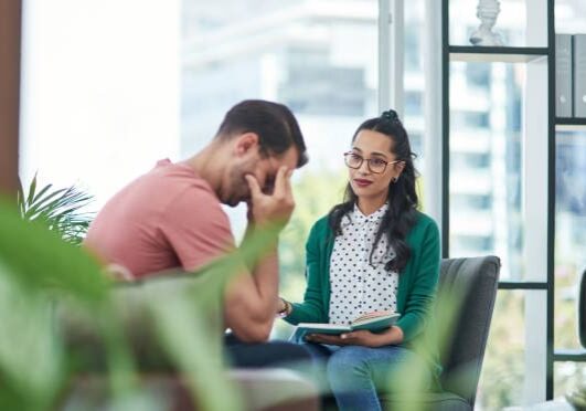 Shot of a young man crying while having a discussion with a woman in a modern office